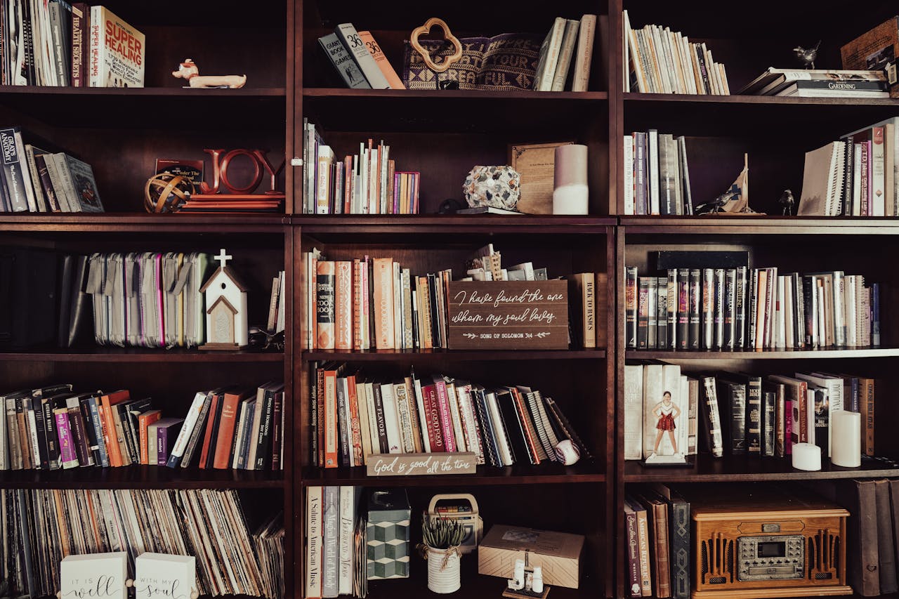 Warm-toned bookshelf filled with diverse books, religious decor, and trinkets.